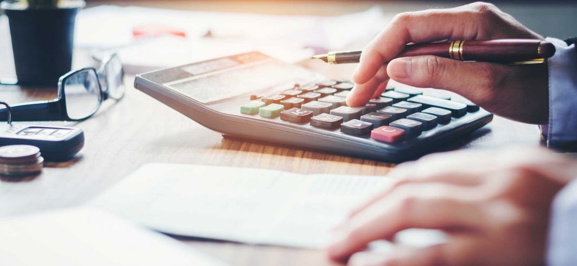 Man using a calculator to add up the costs of publishing a book