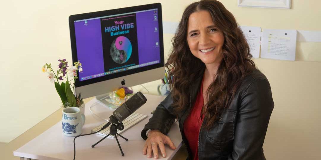 Laura Di Franco smiling in front of a microphone and computer display